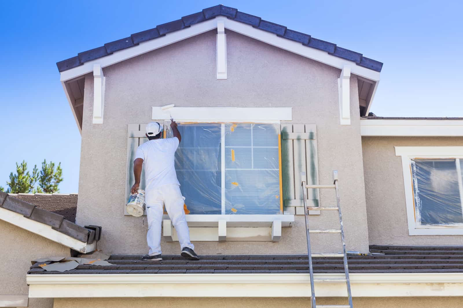 man painting the exterior wall of home